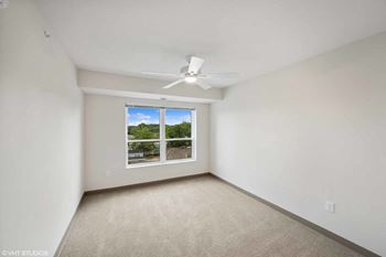 an empty living room with a window and a ceiling fan